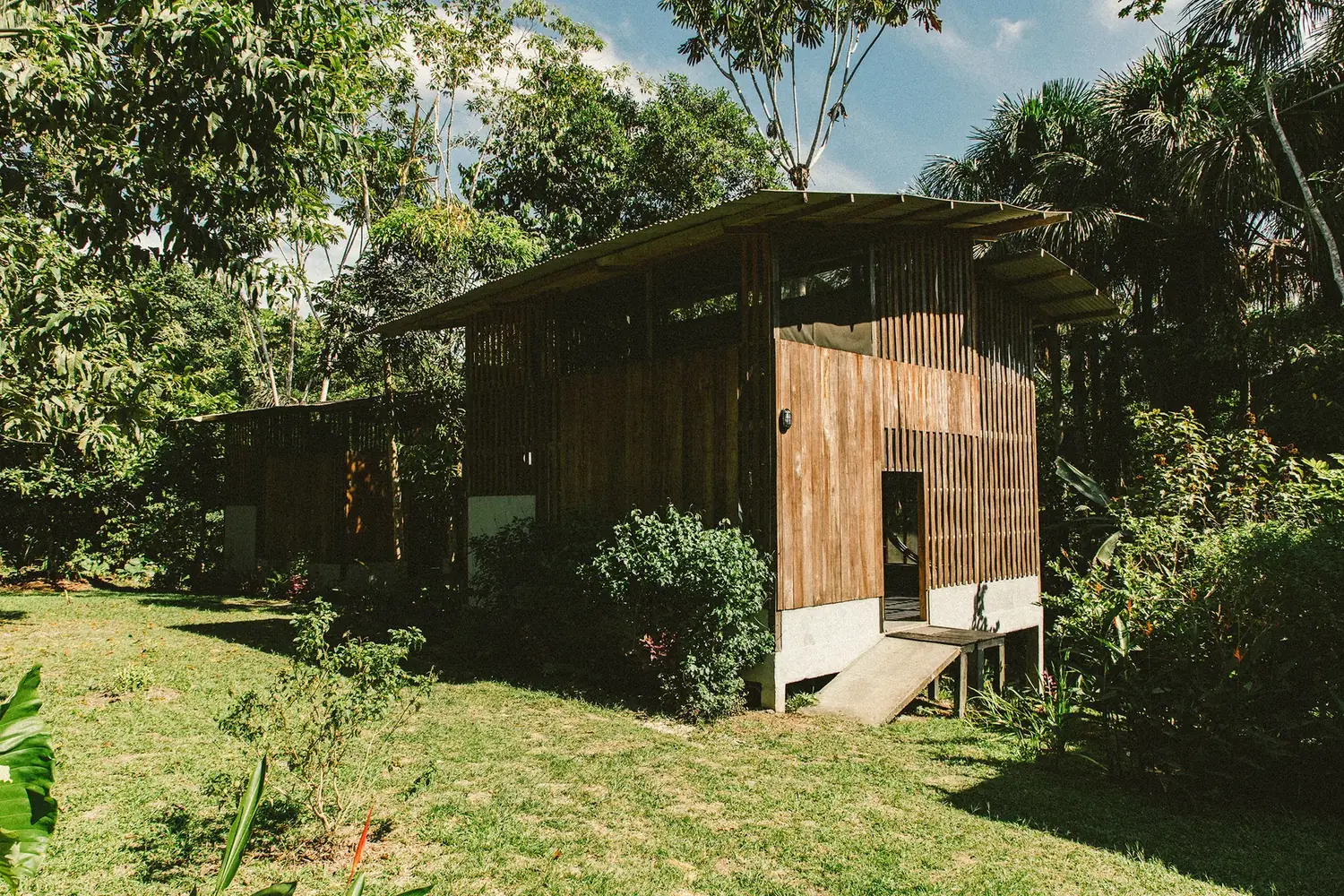Fachada de una cabaña de Amazona Lodge rodeada de vegetación